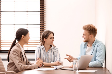 Female insurance agent consulting young couple in office