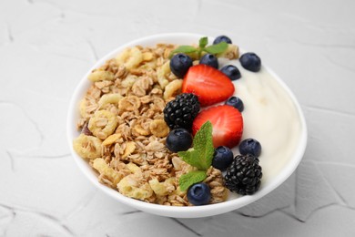 Photo of Tasty oatmeal, yogurt and fresh berries in bowl on white textured table, closeup. Healthy breakfast