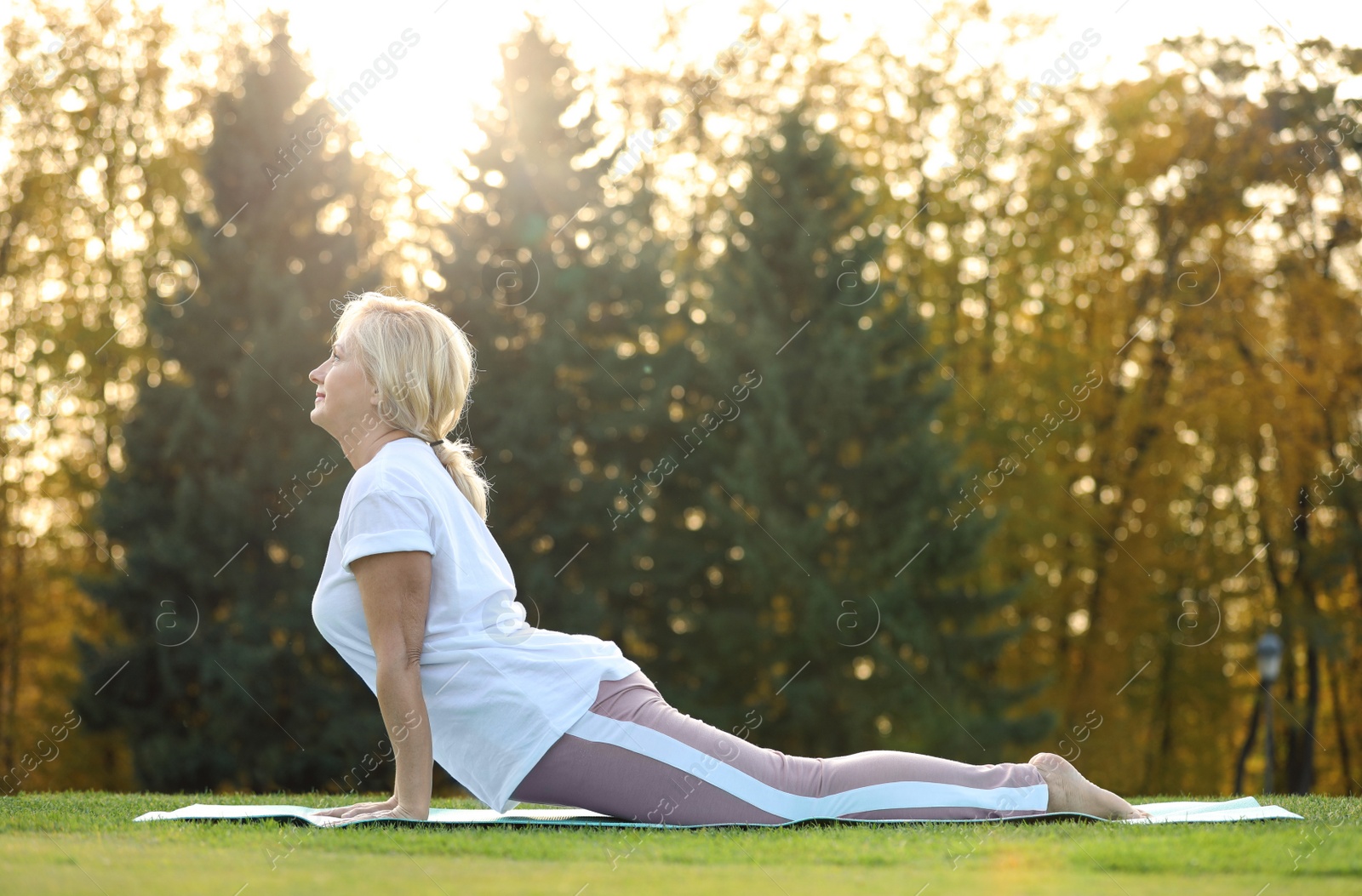 Photo of Happy mature woman practicing yoga in park. Active lifestyle