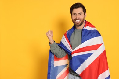 Man with flag of United Kingdom on yellow background, space for text