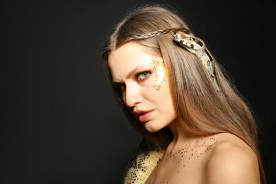 Photo of Beautiful woman with boa constrictor on black background