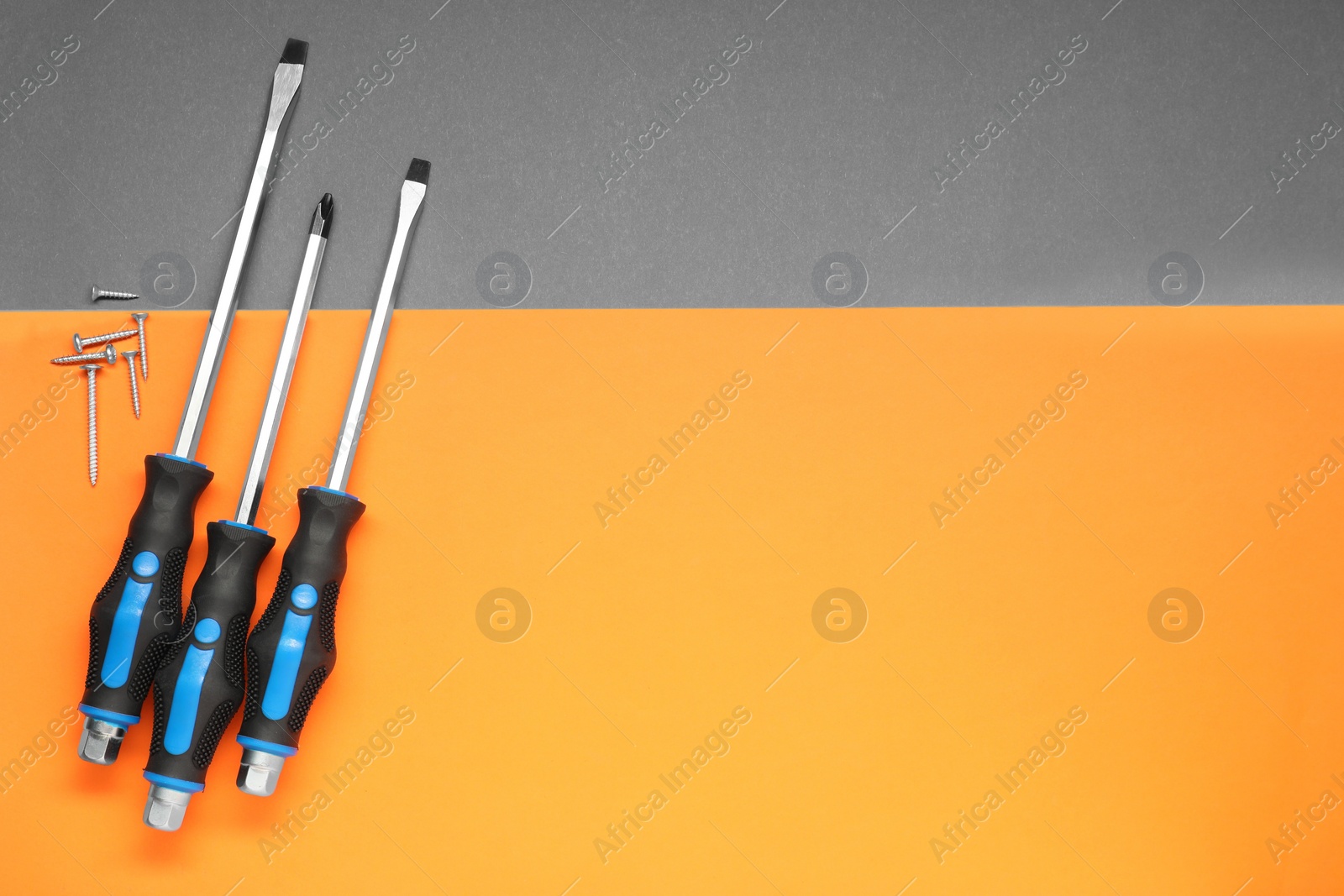 Photo of Set of screwdrivers and screws on color background, flat lay. Space for text