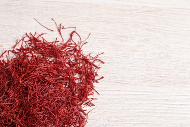 Photo of Dried saffron on white wooden table, flat lay. Space for text