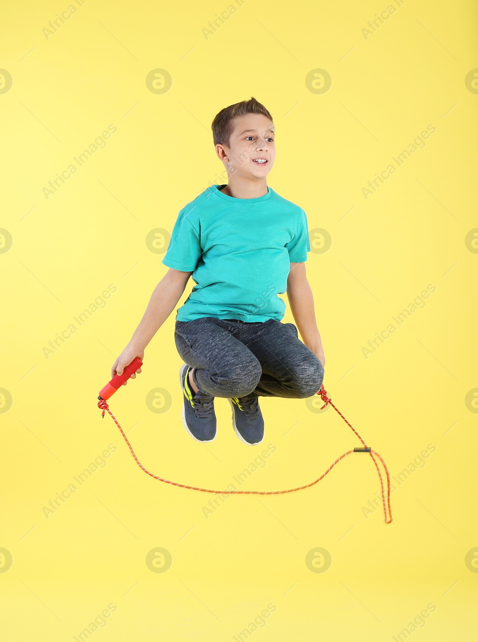 Photo of Full length portrait of boy jumping rope on color background