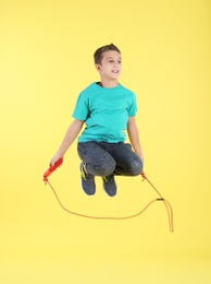 Full length portrait of boy jumping rope on color background