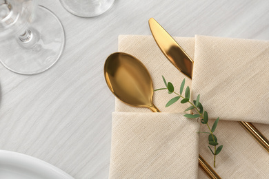 Photo of Elegant cutlery with green leaves on table, flat lay. Festive setting