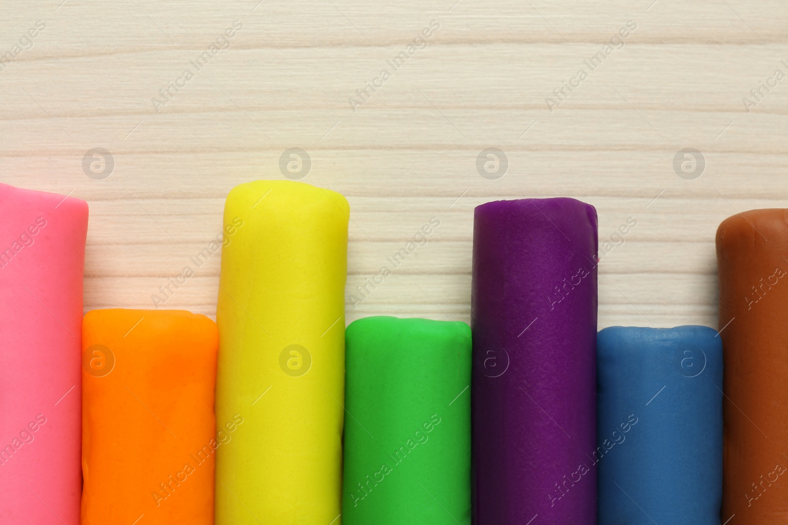 Photo of Different color play dough on wooden table, flat lay