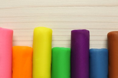 Photo of Different color play dough on wooden table, flat lay