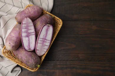 Photo of Purple daikon radishes in wicker basket on wooden table, top view. Space for text
