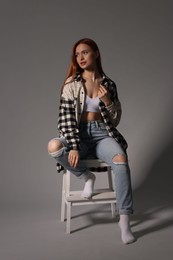 Photo of Beautiful young woman sitting on decorative ladder against gray background