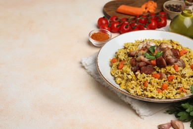 Photo of Delicious pilaf with meat, carrot and garlic on beige textured table. Space for text