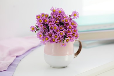 Photo of Cup with beautiful flowers on white table