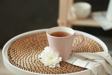 Photo of Cup of tea and flower on table indoors