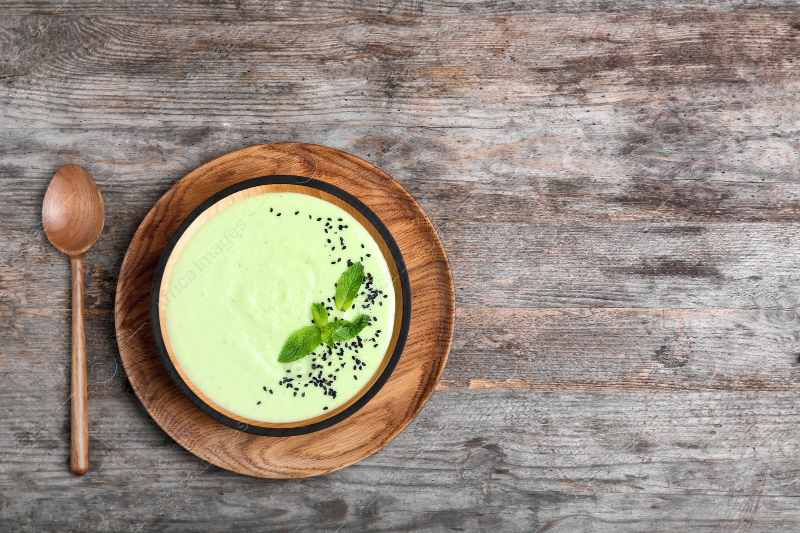 Photo of Green pea soup in bowl on wooden background, top view