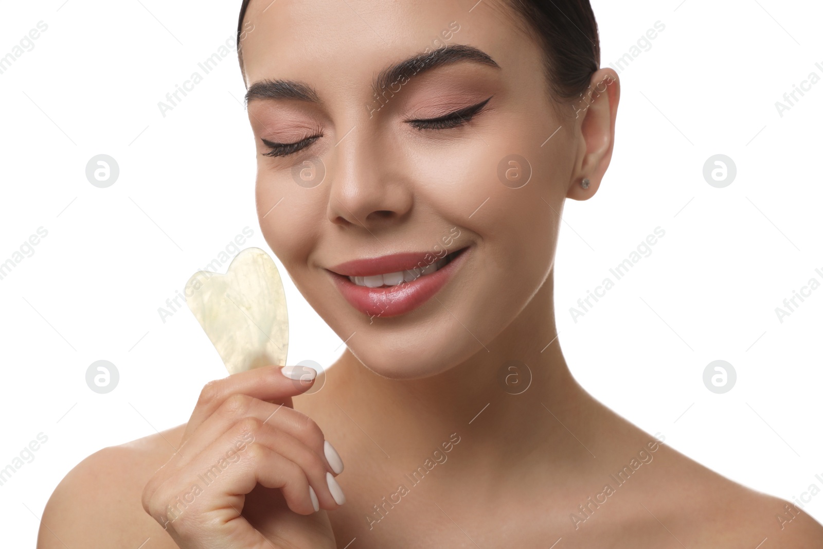 Photo of Beautiful young woman doing facial massage with gua sha tool on white background, closeup