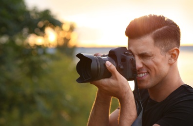 Photographer taking picture with professional camera in countryside