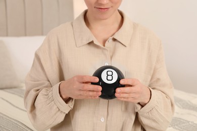 Photo of Woman holding magic eight ball indoors, closeup