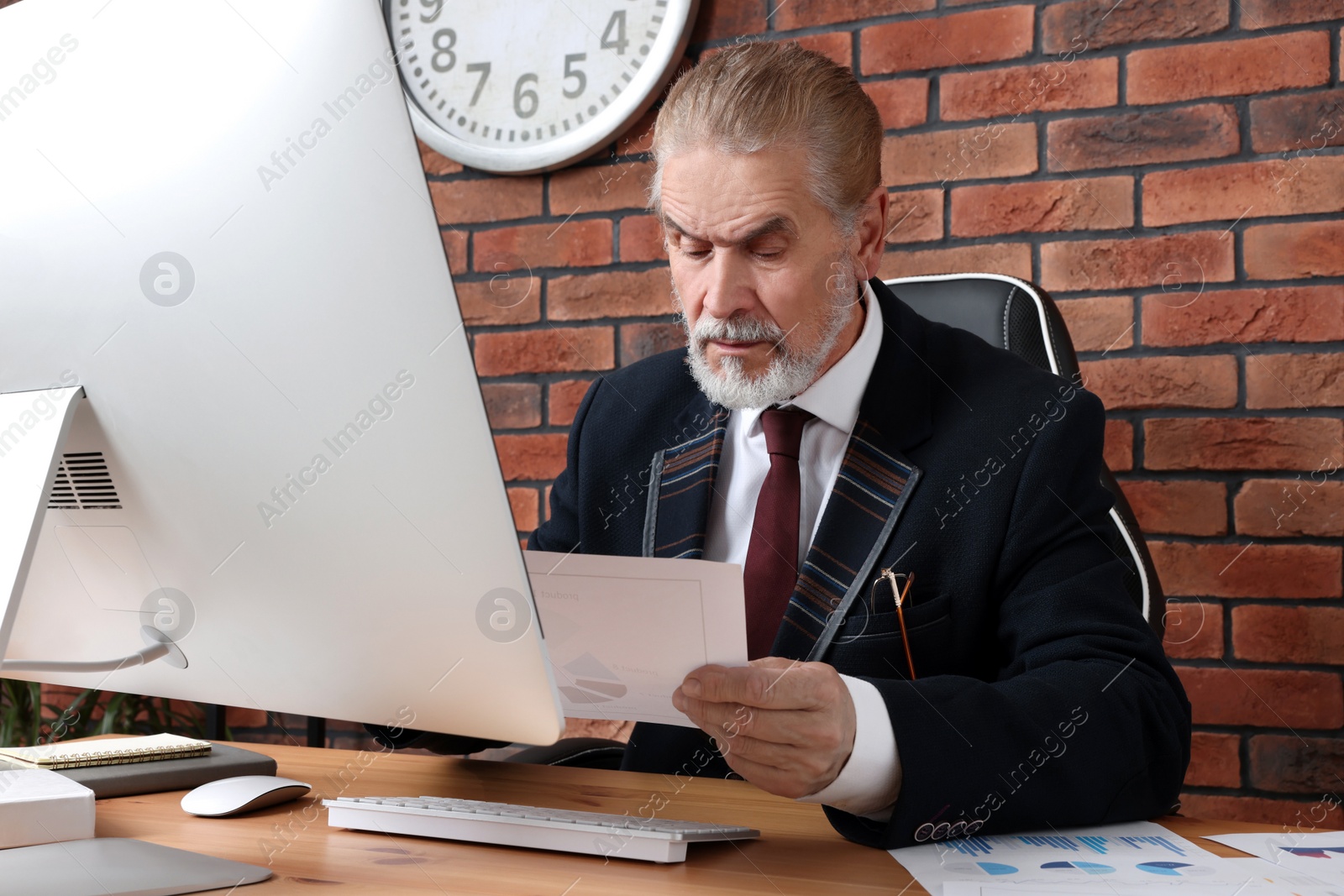 Photo of Serious senior boss working in his office