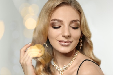 Photo of Beautiful young woman with elegant jewelry against defocused lights