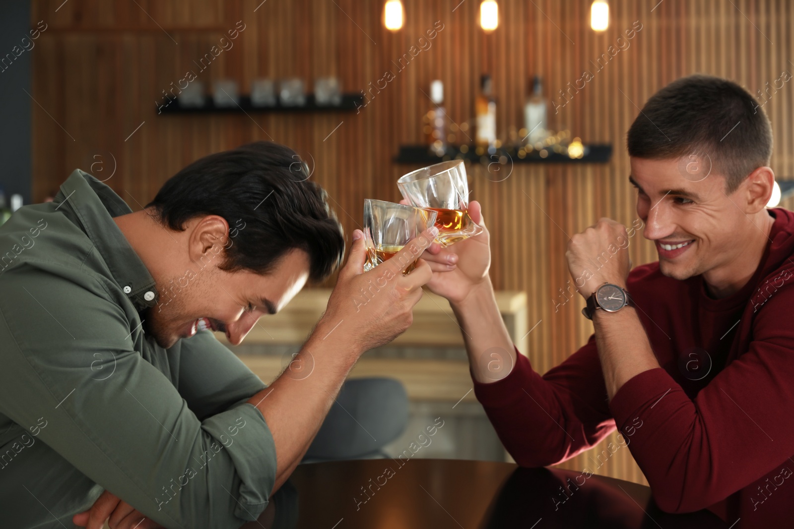 Photo of Young men drinking whiskey together in bar