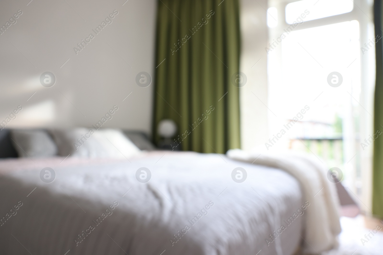 Photo of Blurred view of large bed near window in room