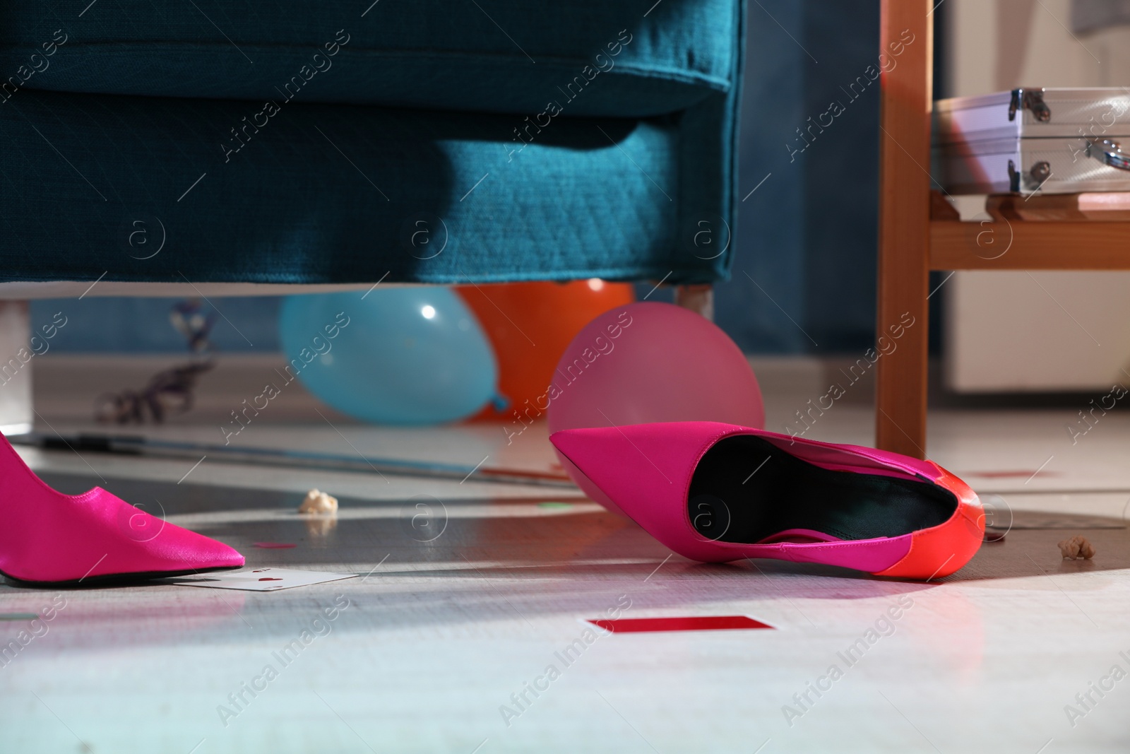 Photo of Pink shoes and playing cards on floor in messy room after party