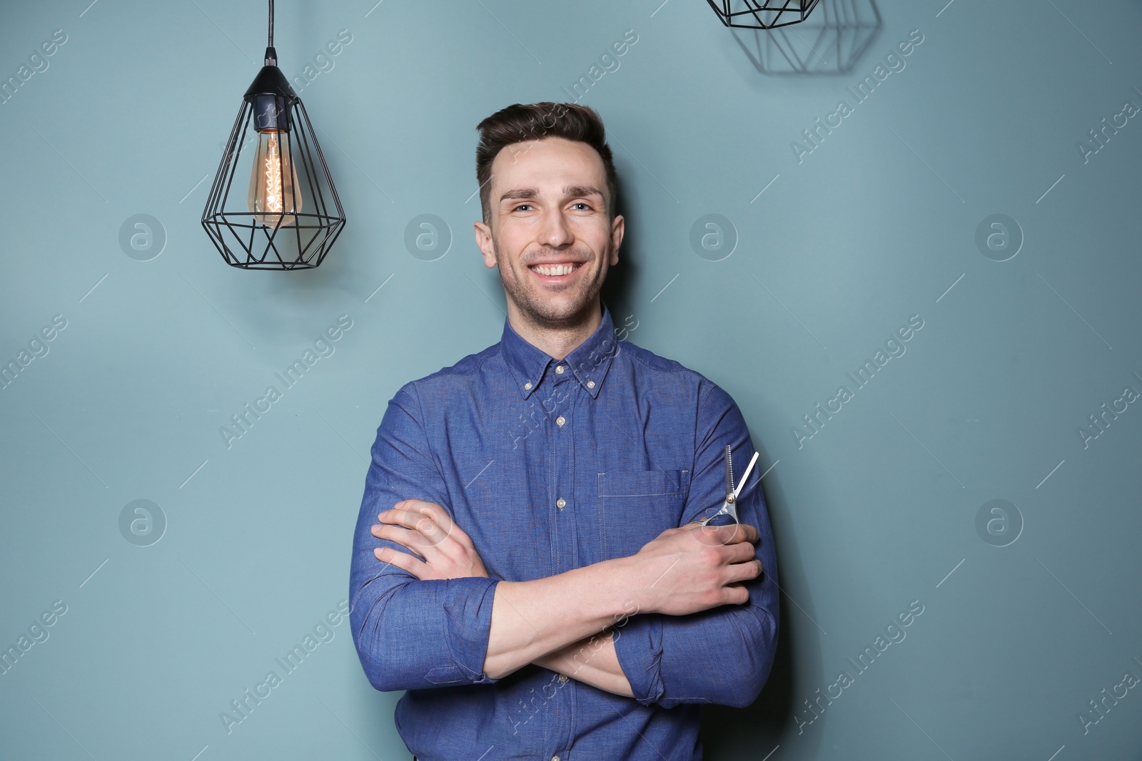 Photo of Professional hairdresser with scissors on color background