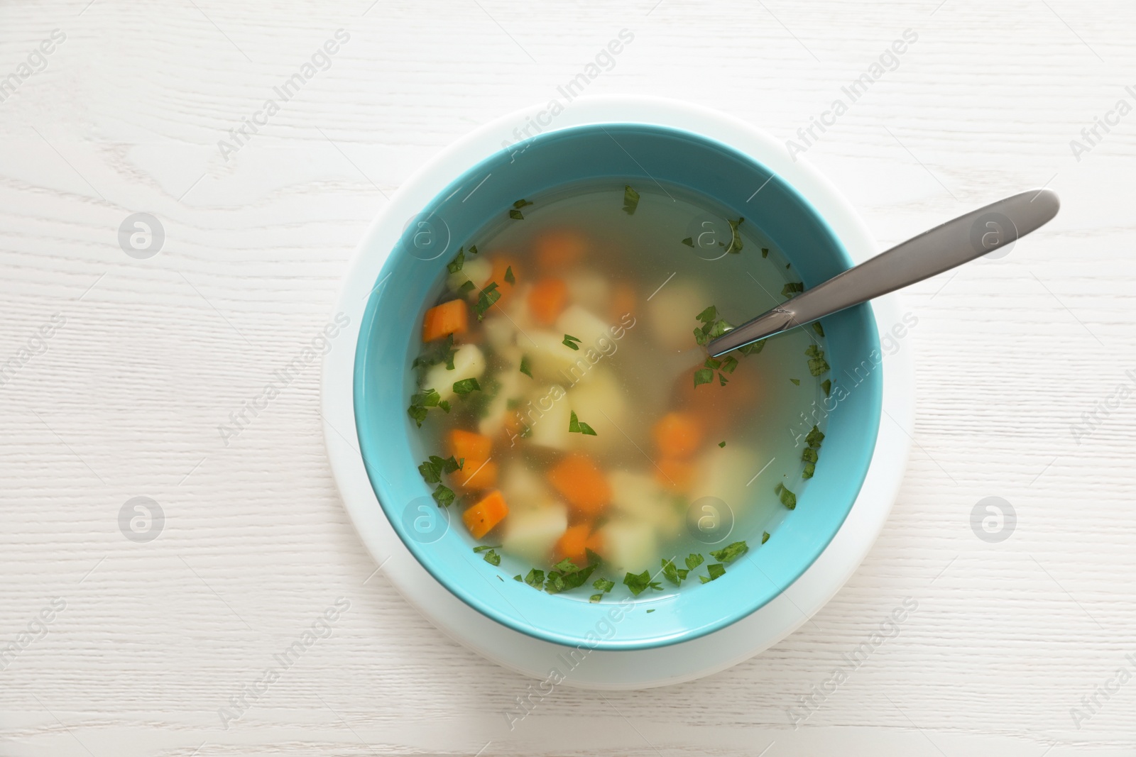 Photo of Bowl of fresh homemade soup to cure flu on wooden table, top view
