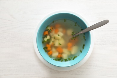 Bowl of fresh homemade soup to cure flu on wooden table, top view