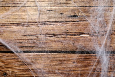 Creepy white cobweb hanging on wooden wall