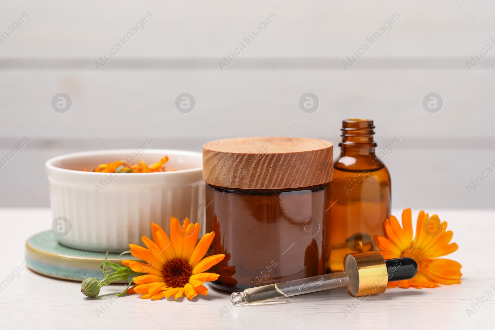 Photo of Different cosmetic products with beautiful calendula flowers on white table