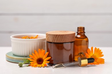 Photo of Different cosmetic products with beautiful calendula flowers on white table