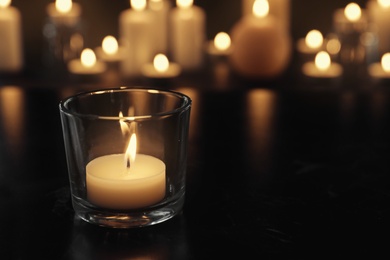 Photo of Burning candle on table in darkness, space for text. Funeral symbol