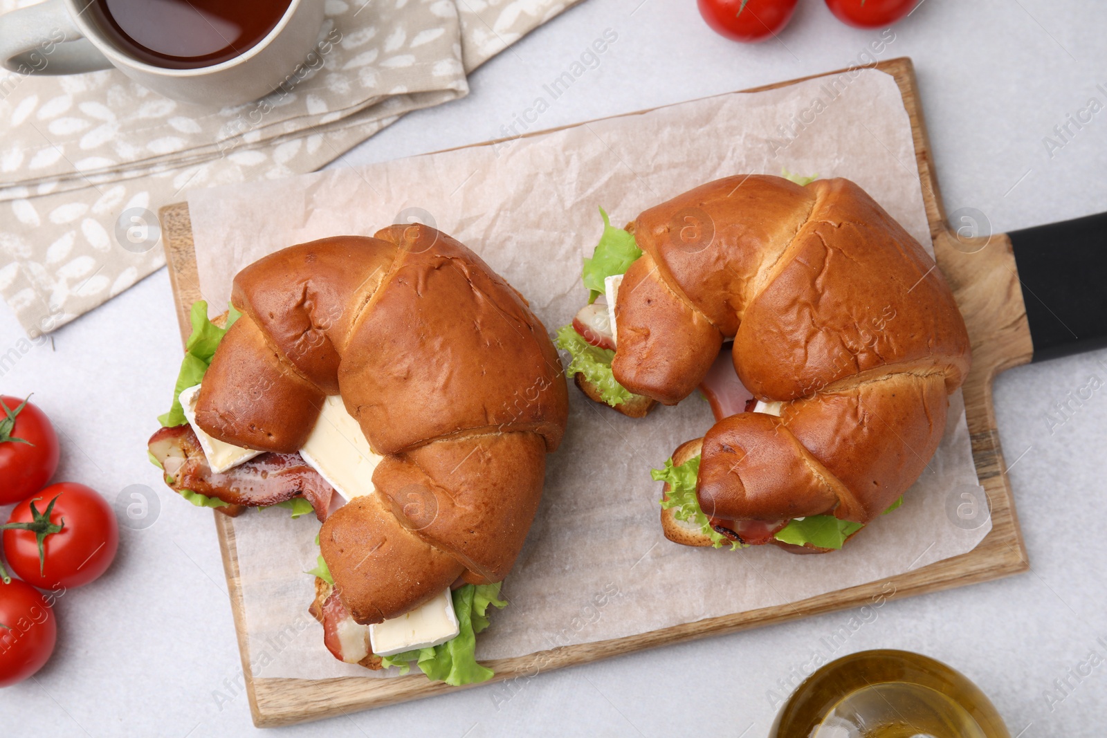 Photo of Tasty crescent rolls with brie cheese, ham and bacon on white table, flat lay