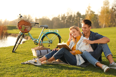 Happy young couple reading book while having picnic outdoors