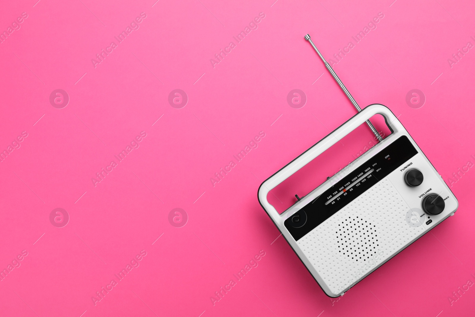 Photo of Retro radio receiver on pink background, top view. Space for text