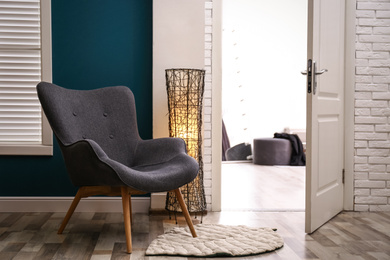 Comfortable armchair with floor lamp and rug indoors