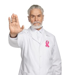 Photo of Mammologist with pink ribbon showing stop gesture on white background. Breast cancer awareness