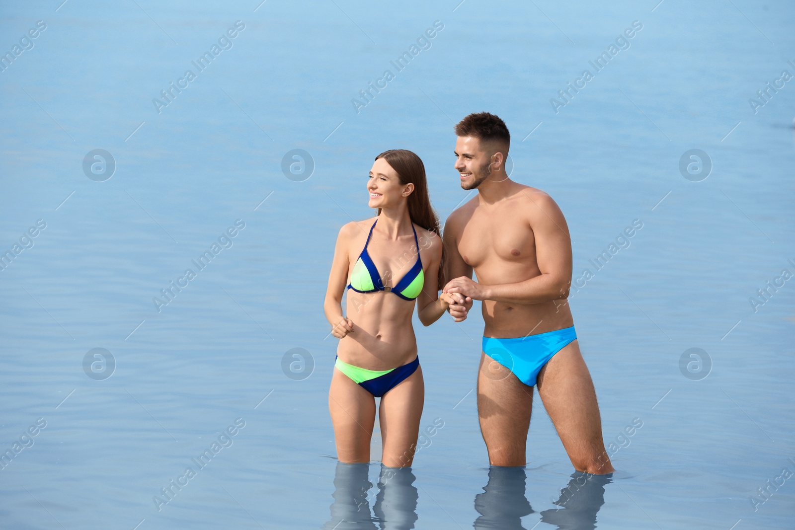 Photo of Young woman in bikini with her boyfriend in sea, space for text. Lovely couple