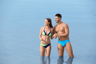 Young woman in bikini with her boyfriend in sea, space for text. Lovely couple