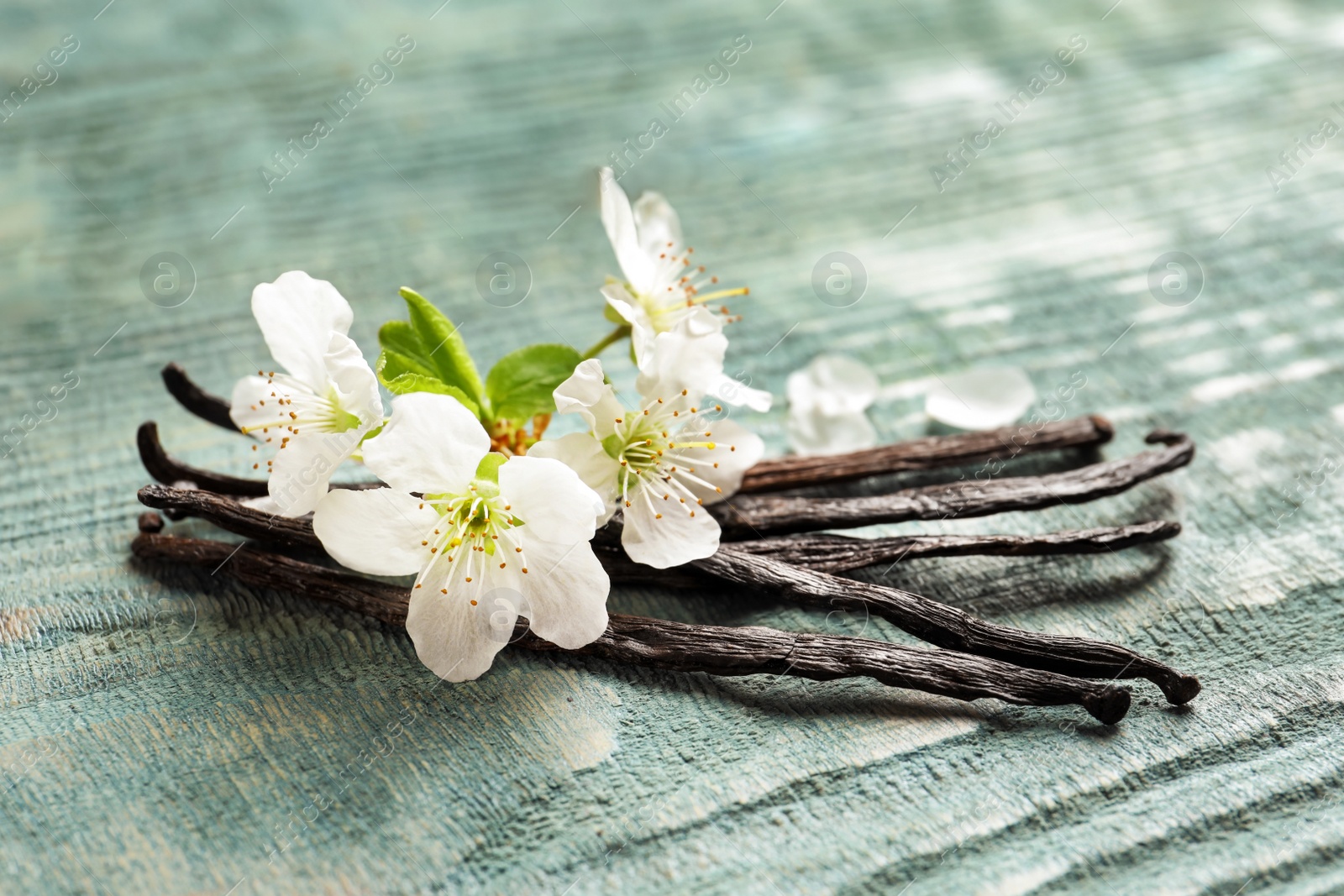 Photo of Vanilla sticks and flowers on wooden background