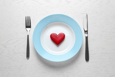 Plate with red wooden heart and cutlery on white background, flat lay. Healthy diet concept