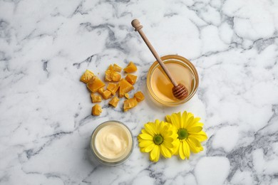 Photo of Natural beeswax, cream, honey and flowers on white marble table, flat lay