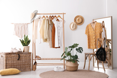 Photo of Rack with stylish women's clothes and mirror indoors. Interior design