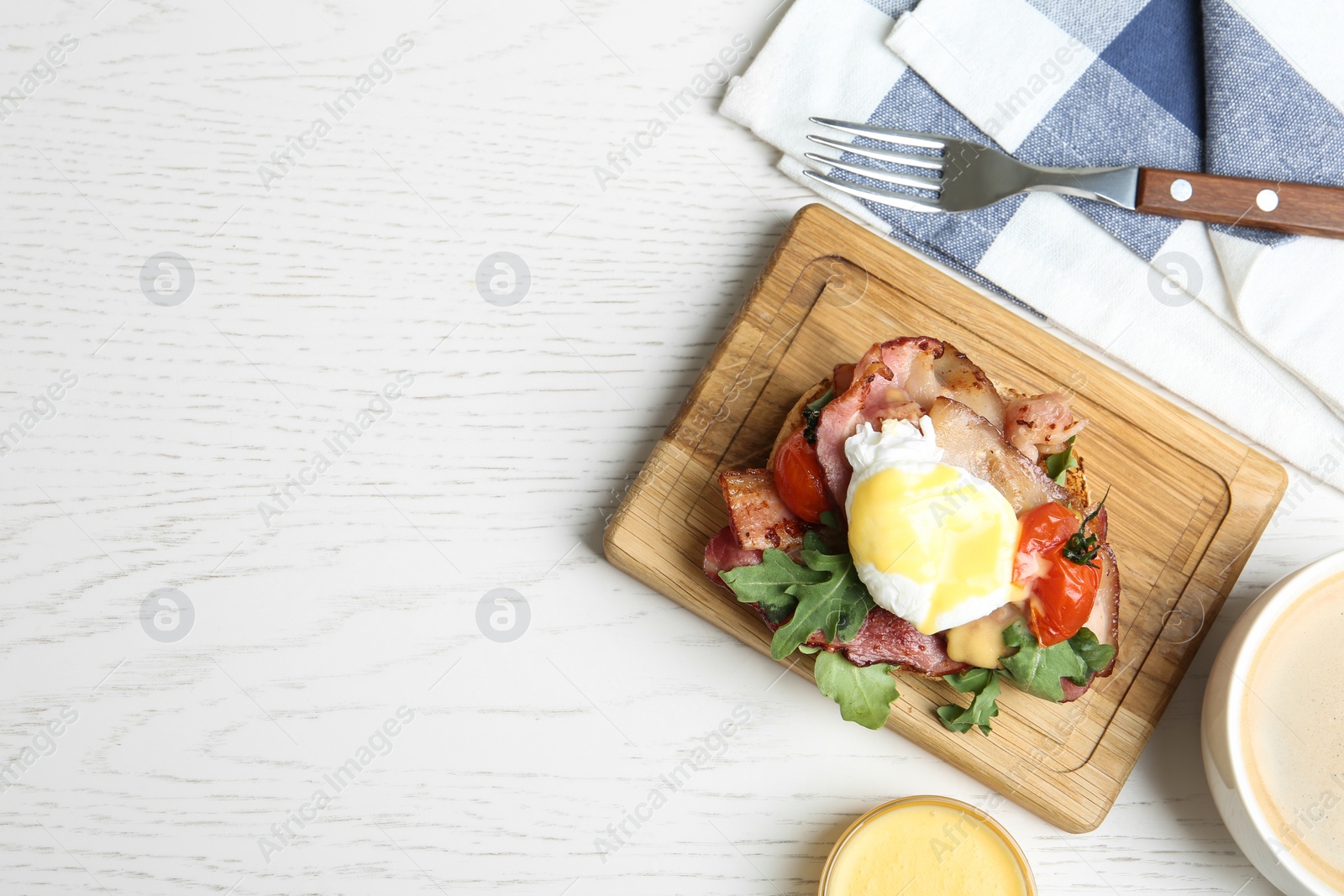 Photo of Delicious egg Benedict served on white wooden table, flat lay. Space for text