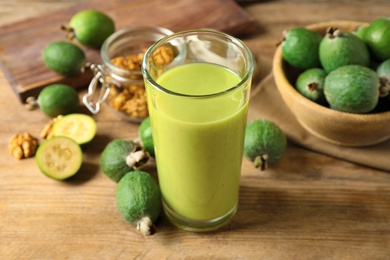 Photo of Fresh feijoa smoothie in glass on wooden table, closeup