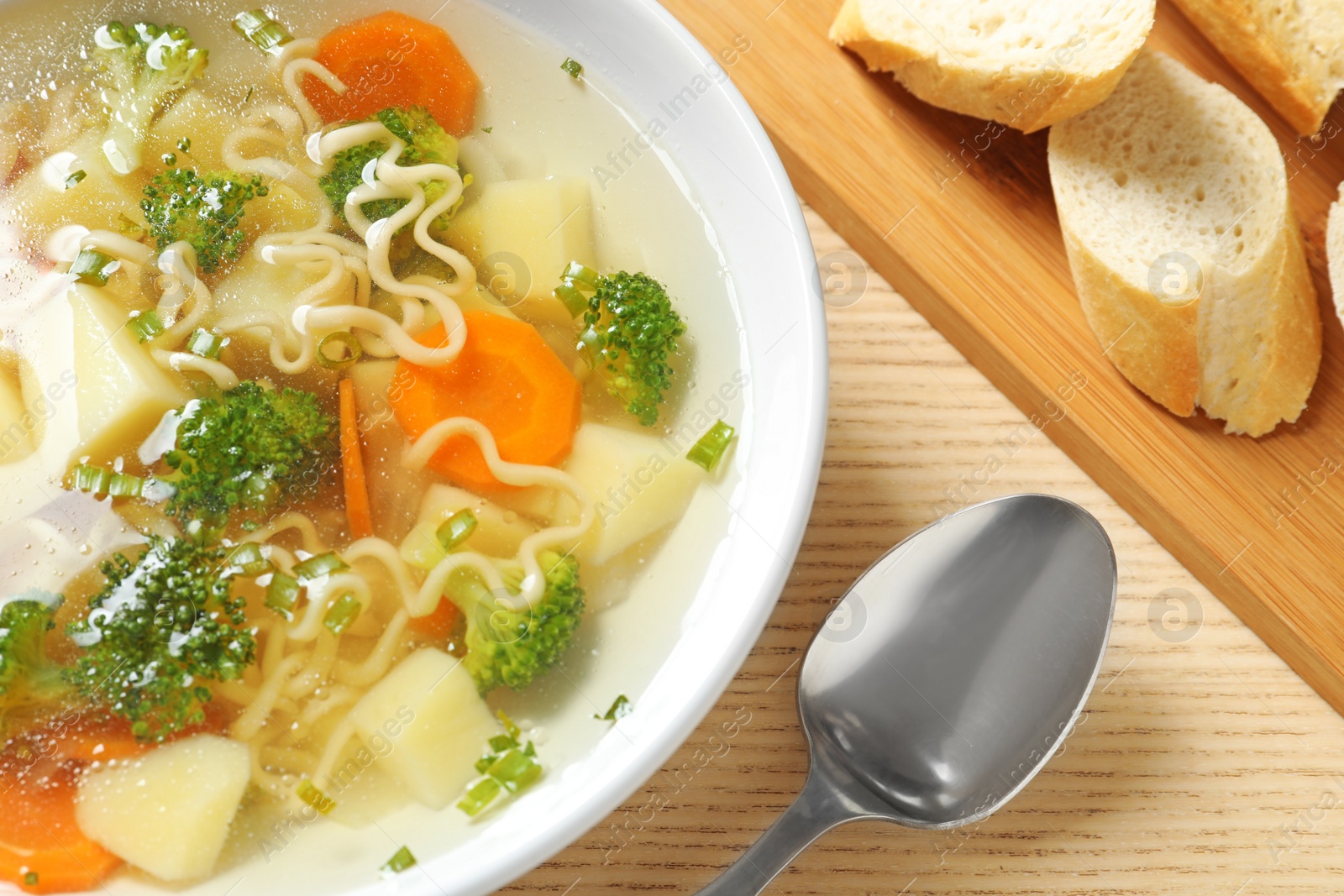 Photo of Bowl of fresh homemade vegetable soup served on wooden table, closeup