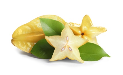 Photo of Cut and whole carambolas with green leaves on white background