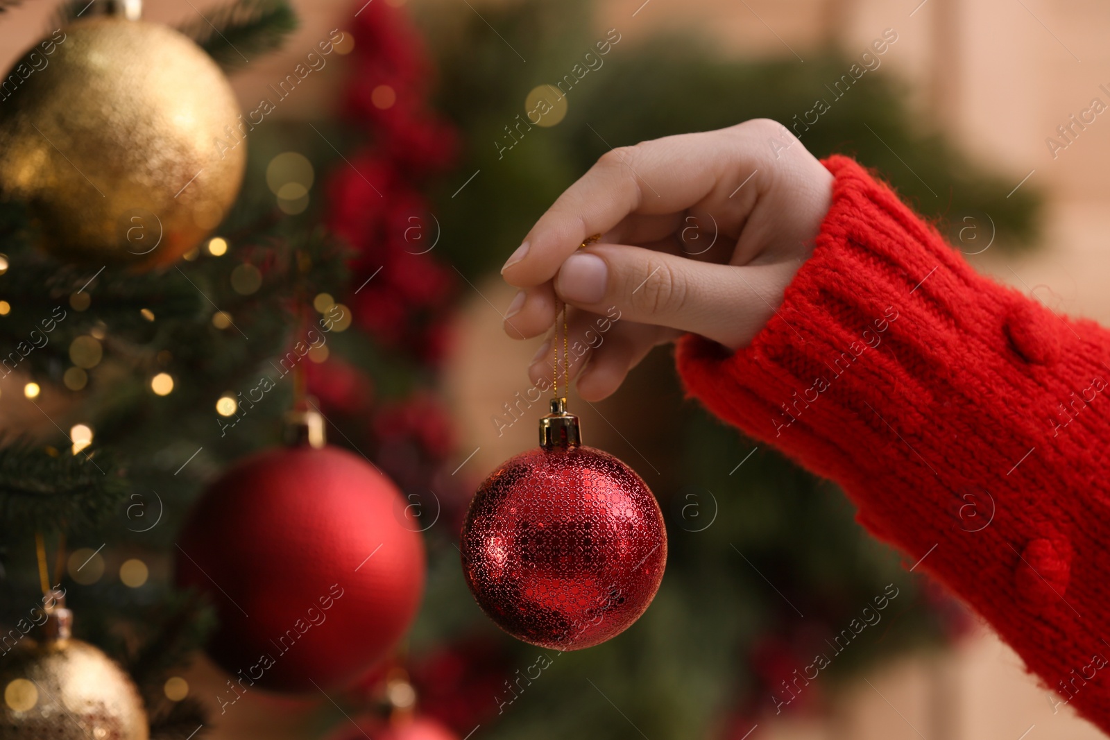 Photo of Woman holding red ball near Christmas tree, closeup