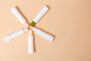 Photo of Flat lay composition with hygienic lipsticks on color background